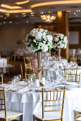 Table at a luxury wedding reception. Beautiful flowers on the table. Serving dishes, glass glasses, waiters work.