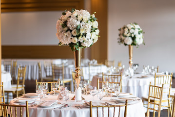 Table at a luxury wedding reception. Beautiful flowers on the table. Serving dishes, glass glasses, waiters work.