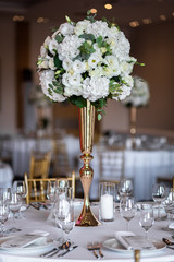 Table at a luxury wedding reception. Beautiful flowers on the table. Serving dishes, glass glasses, waiters work.