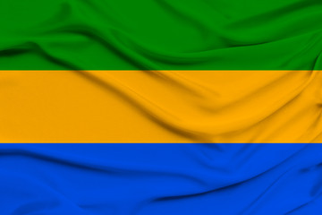 beautiful photo of the national flag of Gabon on delicate shiny silk with soft draperies, the concept of state power, country life, horizontal, close-up, copy space