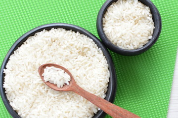 Natural raw white rice grains, on display in bowl and wooden spoon