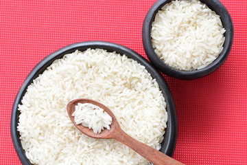 Natural raw white rice grains, on display in bowl and wooden spoon