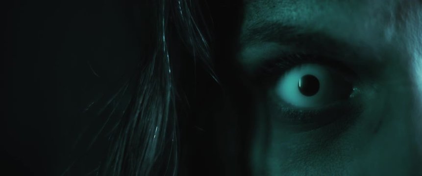 Terrifying creepy zombie woman, close up of white eye opening. Scary look.