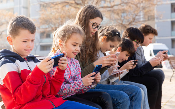 Group of children communicate using smartphones in the playground