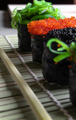Gunkan maki  (sushi rolls) with green seaweed and red caviar of flying fish; Japanese food