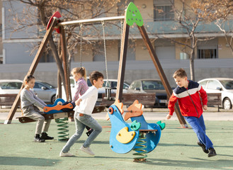 Children are teetering on the swing in the playground