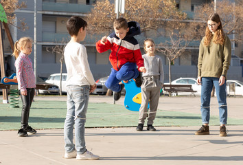 Fototapeta premium Energetic kids playing and skipping on elastic jumping rope in european yard