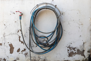 garden hose connected to a tap on a white wall