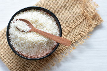 Natural raw white rice grains, on display in bowl and wooden spoon
