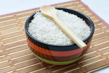 Natural raw white rice grains, on display in bowl and wooden spoon