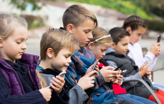 Outdoor portrait of girls and boys playing with phones