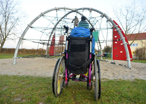 Boy In A Wheelchair Watching Kids On A Playground