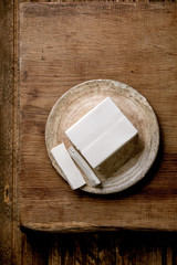 Silk tofu japanese soy cheese whole piece on ceramic plate with chopsticks over wooden table. Flat lay, space