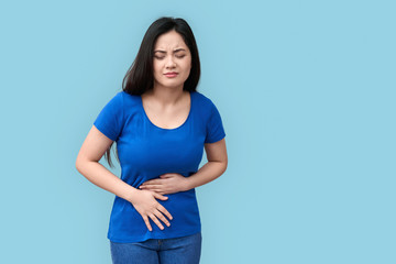 Young adult asian girl standing with spasm in stomach