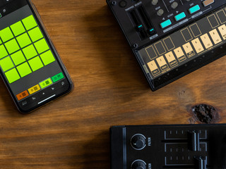 Fototapeta premium Top view of fm synthesizer, midi controller and smartphone with drum machine application on a wooden table Electronic music concept