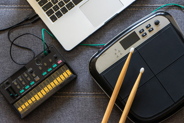 Top view of electronic battery with drumsticks, an fm synthesizer and a laptop. Music concept