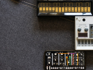 Top view of analog synthesizers and smartphones with virtual modular synthesizer on top of a sofa...