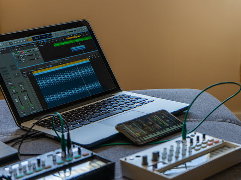 Close up view of fm synthesizer, sampler, smartphone with modular synthesizer and laptop with open audio editor Electronic music concept.