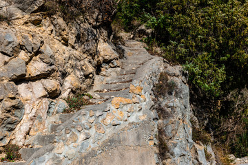 A medieval stone stairway in a forest next to an old French Alpine village