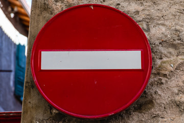 A close-up shot of a 'no entry' road sign on an on old stone wall in a medieval French village