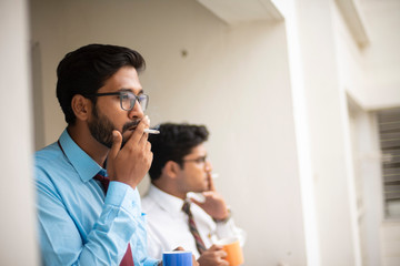 Fototapeta premium Corporate meetings with coffee/tea between young and energetic Indian Bengali bosses/officers/managers and secretary at balcony of the office building regarding a project. Indian corporate lifestyle