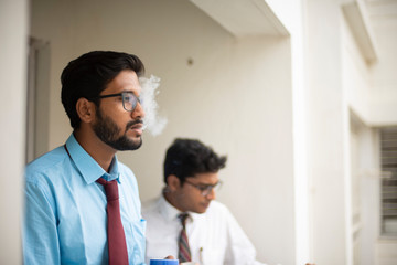 Obraz premium Corporate meetings with coffee/tea between young and energetic Indian Bengali bosses/officers/managers and secretary at balcony of the office building regarding a project. Indian corporate lifestyle