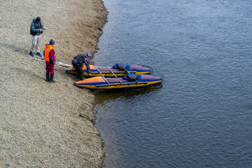 Tourists prepare catamarans for rafting on a mountain river.