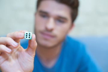 young man holding dice showing number six