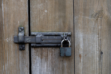 Texture od wooden door made of antique wood. Raw wood after century. Metal gate with padlock.