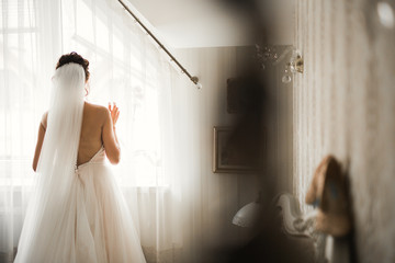 Gorgeous bride in robe posing and preparing for the wedding ceremony face in a room