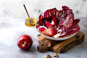 Colorful pink salad with apple, radicchio, pecan nuts, watermelon radish, fennel and pomegranate. Healthy vegetarian meal.