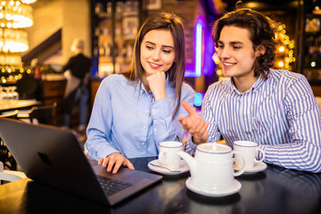 Young couple have fun while looking on laptop at cafe