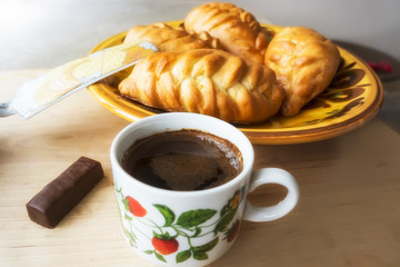 A Cup of coffee with candy and pies in the background