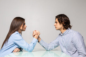 Beautiful couple doing arm wrestling challenge isolated on white background
