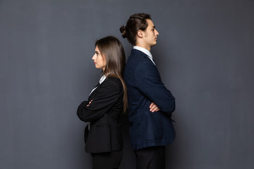 Business man and woman standing back to back isolated on gray background. Teamwork concept