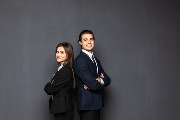 Business man and woman standing back to back isolated on gray background. Teamwork concept