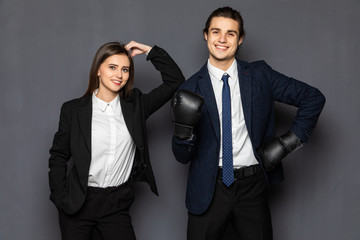 Business man with boxing gloves with a young business woman isolated on gray background