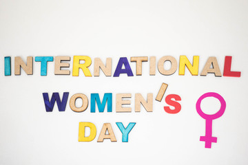 International Women's Day, phrase made from wooden letters and female gender symbol made from paper on white background