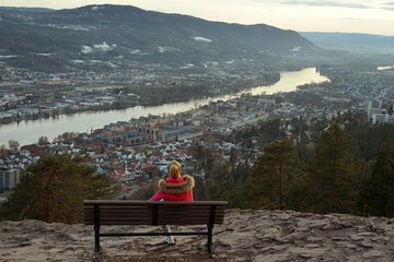 A woman back sitting on the bench and watching the scenery view in Drammen city, Norway.
