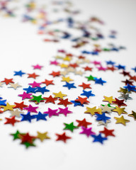 Confetti stars on white background, festive colorful and shiny stars on white background with copy space.