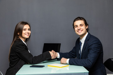 Friendly smiling businessman and businesswoman handshaking over the office desk after pleasant talk and effective negotiation, good relationship, making deal, hiring. Business concept.