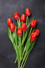 Beautiful red tulips on a dark stone table. Spring background. Top view. Copy space