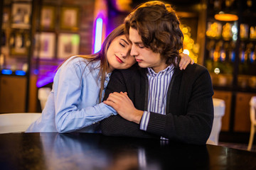 Pleased young loving couple in cafe hugging.