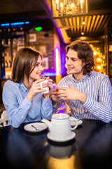 Portrait of affectionate young couple in stylish clothes having coffee in cafe