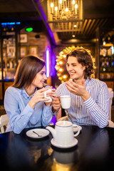 Happy young man and woman drinking tea in cafe