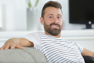 smiling young man relaxing on sofa at home