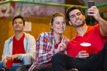 sports supporters taking selfie in the stands
