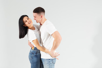 A happy girl with her boyfriend, they are dancing and having fun. Attractive young woman and handsome man are enjoying spending time together on white background. Lovely couple. Studio shot