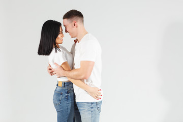 Fototapeta premium A happy girl with her boyfriend, they are dancing and having fun. Attractive young woman and handsome man are enjoying spending time together on white background. Lovely couple. Studio shot