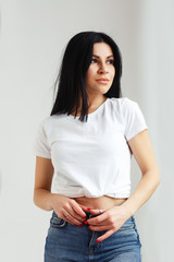Attractive girl posing in studio on white background. Girl in white shirt and jeans. Caucasian brunette young woman. Close up fashiont style portrait. wearing cute trendy outfit. .Fashion concept.